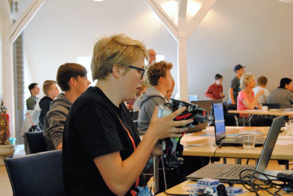 Schüler arbeitet konzentriert an einem Roboter, daneben ein Laptop.
